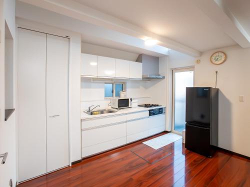 a kitchen with white cabinets and a black refrigerator at JING HOUSE京成高砂駅5分豪華一戸建て最大8人成田羽田直通無料駐車浅草スカイツリー近くtokyo narita in Tokyo