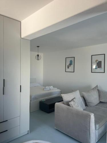 a living room with a couch and a bed at Minimal Grey Apartment Pool-front in Paros in Parikia