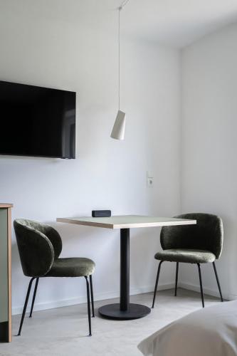 a table with two chairs and a tv on a wall at Lebe' scharnitz in Scharnitz