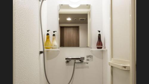 a bathroom with a shower with a sink and a mirror at Dormy Inn Kumamoto Natural Hot Spring in Kumamoto