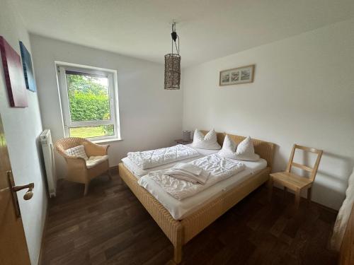 a bedroom with a bed and a chair and a window at Ferienresidenz Am weißen Regen in Bad Koetzting