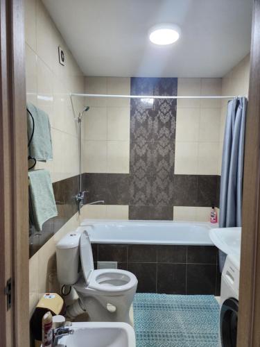 a bathroom with a toilet and a tub and a sink at Apartments Paritet in Bishkek