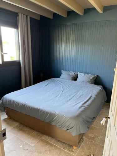 Ce lit se trouve dans une chambre dotée d'un mur bleu. dans l'établissement Le chalet, à Saint-Lubin-en-Vergonnois