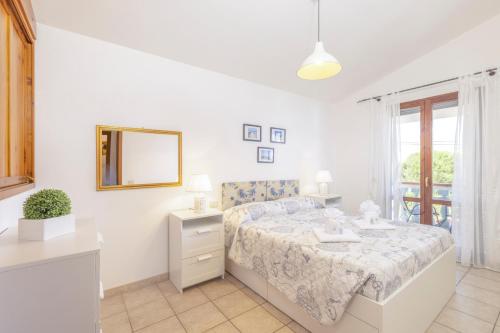 a white bedroom with a bed and a mirror at Casa Calasetta sul porto in Calasetta