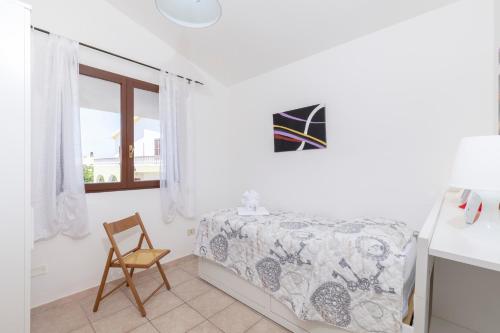 a bedroom with a bed and a chair and a window at Casa Calasetta sul porto in Calasetta