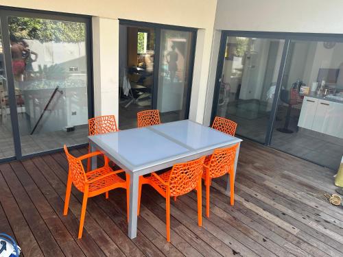 une table et des chaises sur une terrasse avec des fenêtres en verre dans l'établissement Villa climatisé contemporaine 8 personnes, à Jacou