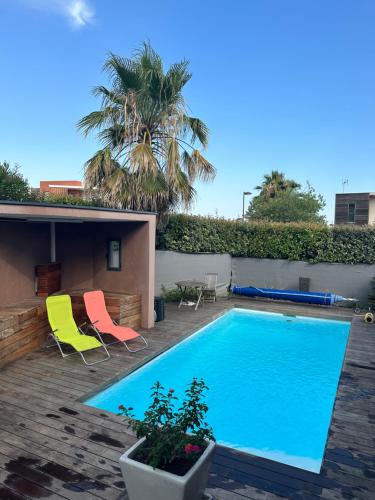 - une piscine avec 2 chaises et un palmier dans l'établissement Villa climatisé contemporaine 8 personnes, à Jacou