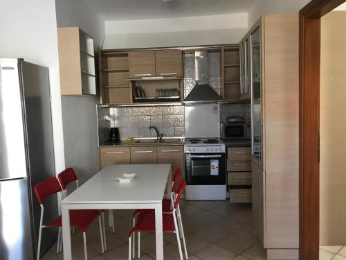 a kitchen with a white table and red chairs at Kali Stalonia in Nikiti