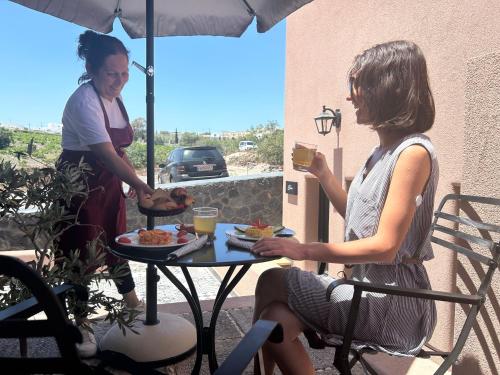 two women standing on a patio with a table with food at Golden Moments Luxury Stone Villas C in Mesaria