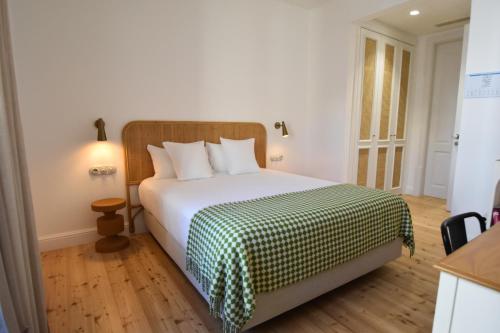 a bedroom with a bed with a green and white blanket at Casa Amor Olhão in Olhão