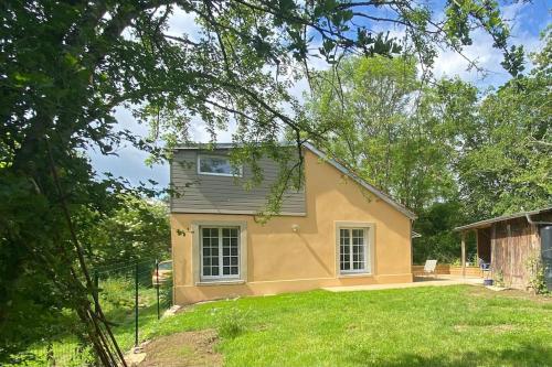 a small yellow house in the middle of a yard at La petite maison in Falaise