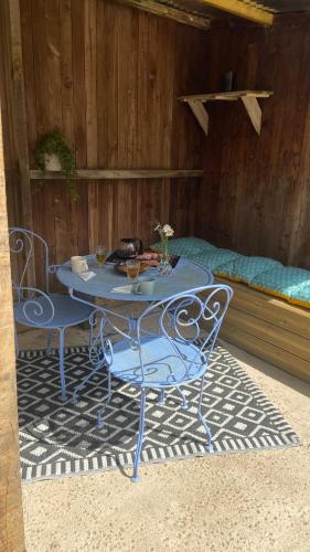 une table bleue et des chaises sur un tapis avec un lit dans l'établissement La petite maison, à Falaise