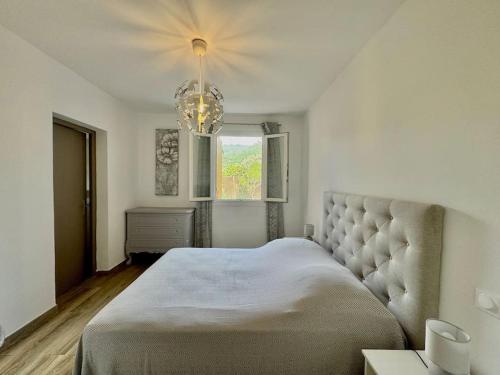 une chambre avec un grand lit et un lustre dans l'établissement Villa Confortable avec Piscine, à San-Gavino-di-Carbini