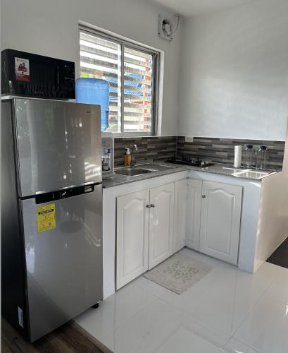 a kitchen with white cabinets and a stainless steel refrigerator at Dolce Residencia in Tacloban