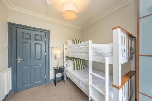 a bedroom with two bunk beds and a blue door at Llywelyn-Fawr in Aberffraw