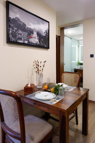 a dining room table with a television on the wall at Alaya Stays Premium 1 BHK - Baljees Melville Utopia in Shimla