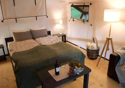 a bedroom with a bed and a table with wine bottles at Glempings Eglenieki in Almale