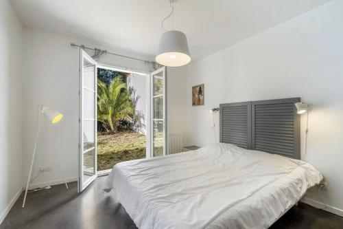une chambre avec un lit et une grande fenêtre dans l'établissement Villa Taru La Palmyre, aux Mathes
