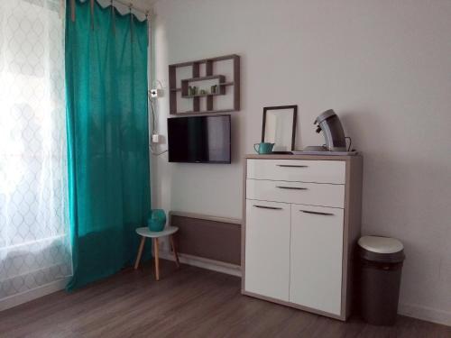 Cette chambre dispose d'une commode blanche et d'une télévision murale. dans l'établissement Bel appartement 4 personnes dans résidence privée avec Parking, au Cap d'Agde