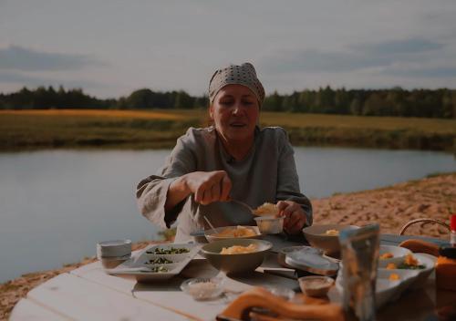 una mujer sentada en una mesa con un plato de comida en Glempings Dīķīši, en Stākas
