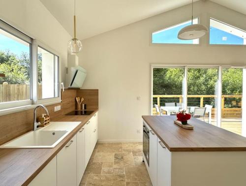 une cuisine avec des placards blancs et une grande fenêtre dans l'établissement Villa à deux pas du lac, à Léon