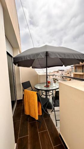 a table and chairs with an umbrella on a balcony at Pink House Martil in Martil