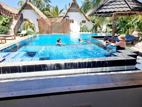 a group of people sitting in a swimming pool at The New Blue Waves Hotel in Jambiani