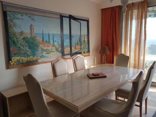 a dining room table with chairs and a painting on the wall at Alania Sea View Apartment in Limassol