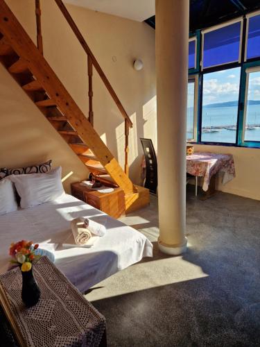 a bedroom with a bed and a staircase with windows at Heart of Balchik in Balchik