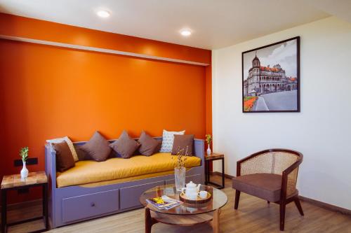 a living room with a yellow couch and a table at Alaya Stays Premium 1 BHK - Baljees Melville Utopia in Shimla