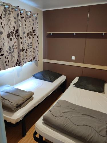 Cette chambre comprend 2 lits et un rideau. dans l'établissement Le Moulin du Pont D'Aliès, à Axat