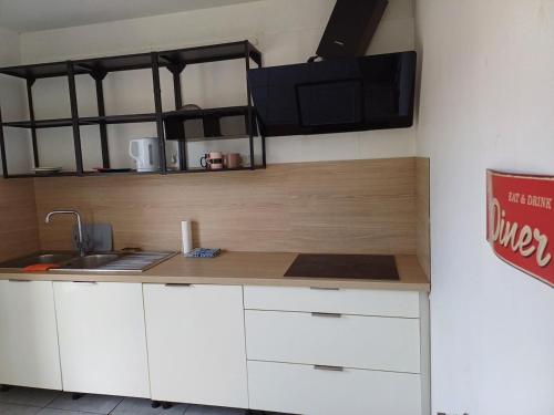 une cuisine avec des armoires blanches et un comptoir dans l'établissement Charmante chambre de hôte en compagne avec jardin, à Souppes-sur-Loing