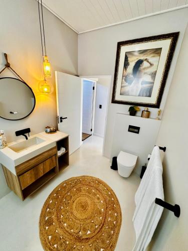 a bathroom with a sink and a mirror and a rug at Thalassophile Beach House - Heated Pool in St. Helena Bay