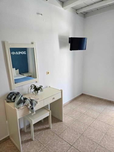 a room with a table and a tv on a wall at Faros Rooms in Loutro
