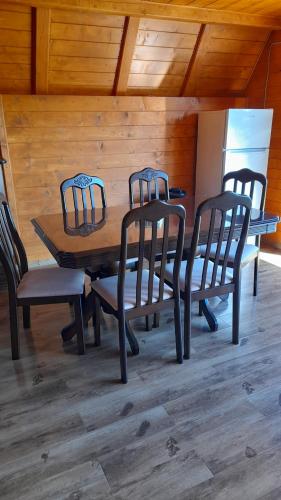 a wooden table with four chairs and a refrigerator at Căbănuța Busuioc Colibita in Bistriţa Bîrgăului