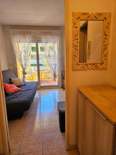 un salon avec un canapé et un miroir dans l'établissement Studio lumineux en plein centre-ville, avec terrasse privée sur cour, situé place du Pin, à Nice