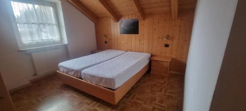 a bedroom with a bed in a room with a window at Appartamenti Casari in Pozza di Fassa