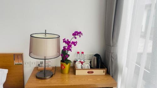 a table with a lamp and a vase with flowers on it at 古北御尚精品民宿Gubeiyushang in Gubeikou