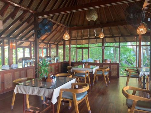 een restaurant met tafels, stoelen en ramen bij Kohtao Heritage Hideaway in Ko Tao