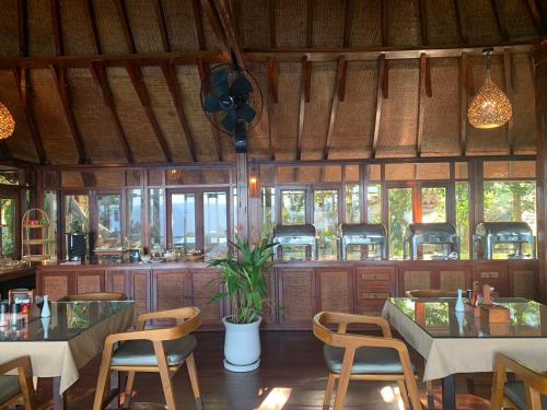 een restaurant met tafels, stoelen en ramen bij Kohtao Heritage Hideaway in Ko Tao