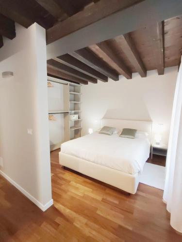 a bedroom with a white bed and wooden floors at CA' DEI BURANELLI - CENTRO CITTA' in Treviso