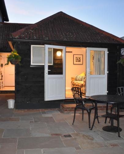 a black and white shed with a table and a couch at FOX'S DEN Dog friendly, self-contained guest suite in Lymington