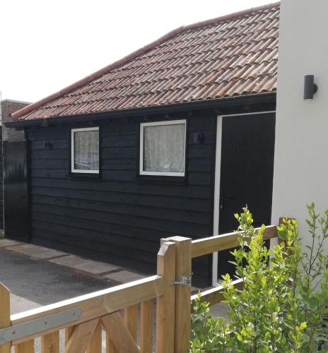 a black house with a wooden fence at FOX'S DEN Dog friendly, self-contained guest suite in Lymington