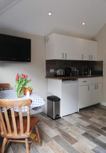 a kitchen with a table with a vase of flowers on it at FOX'S DEN Dog friendly, self-contained guest suite in Lymington