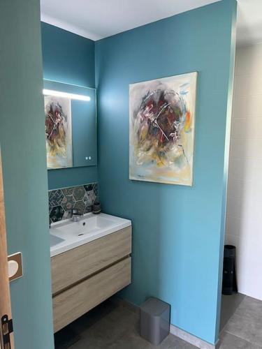 a bathroom with a sink and two pictures on the wall at Villa avec piscine chauffée in Ancy