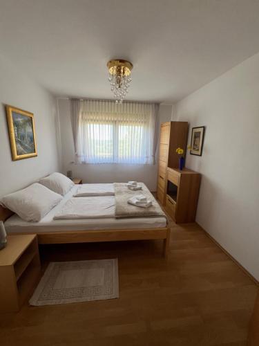 a bedroom with a large bed and a chandelier at Anamarija Apartments in Ličko Petrovo Selo