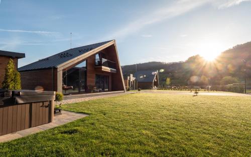 a building in a field with the sun in the background at Luxury Aframe in Râşnov