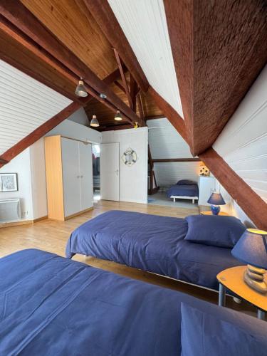 a attic bedroom with two beds and wooden ceilings at Oasis de Sérénité avec piscine in La Baule
