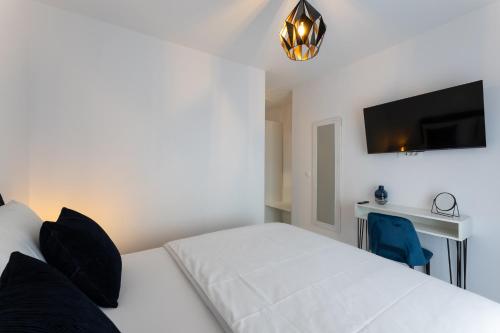 a bedroom with a white bed and a flat screen tv at Holiday Home Izzy in Kaštela