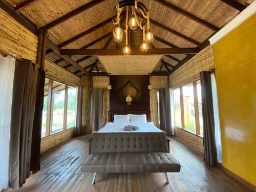a bedroom with a bed in a room with windows at Natu Hut Farm Stay & Cafe' Chiang Mai in Mae Taeng